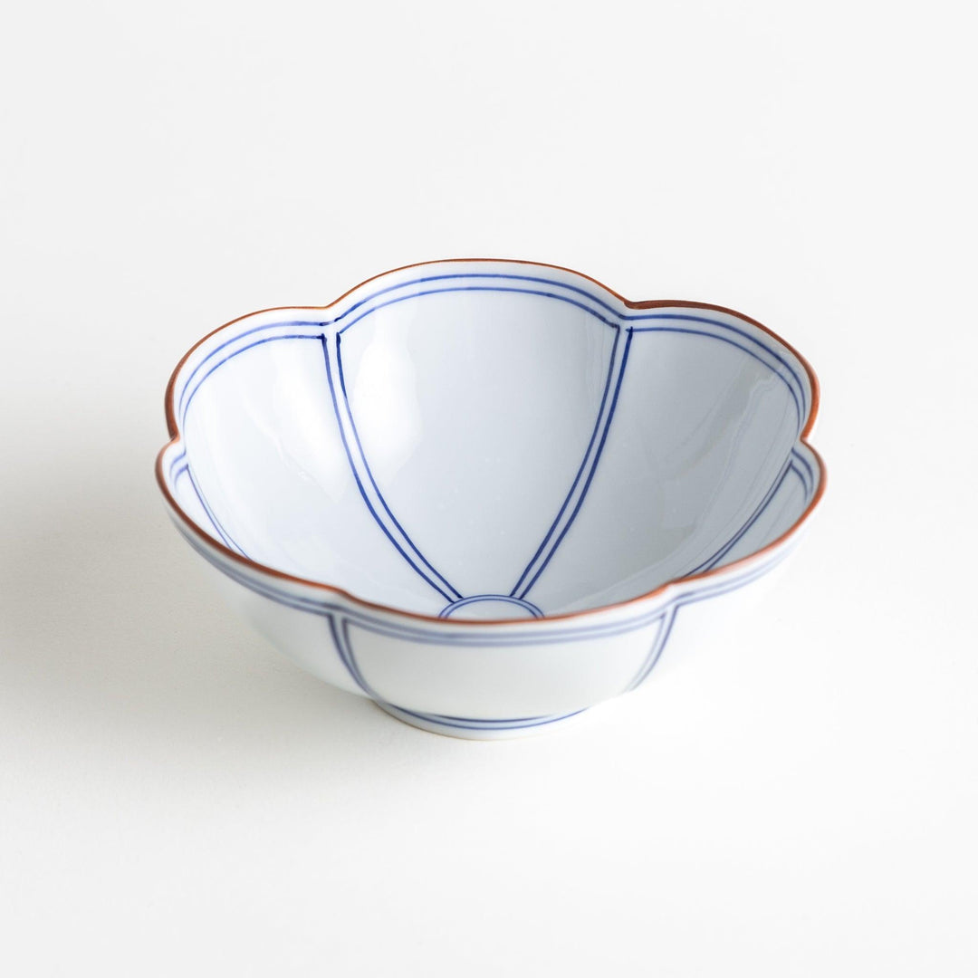 A white ceramic bowl with a floral shape, featuring delicate blue lines and an orange rim.