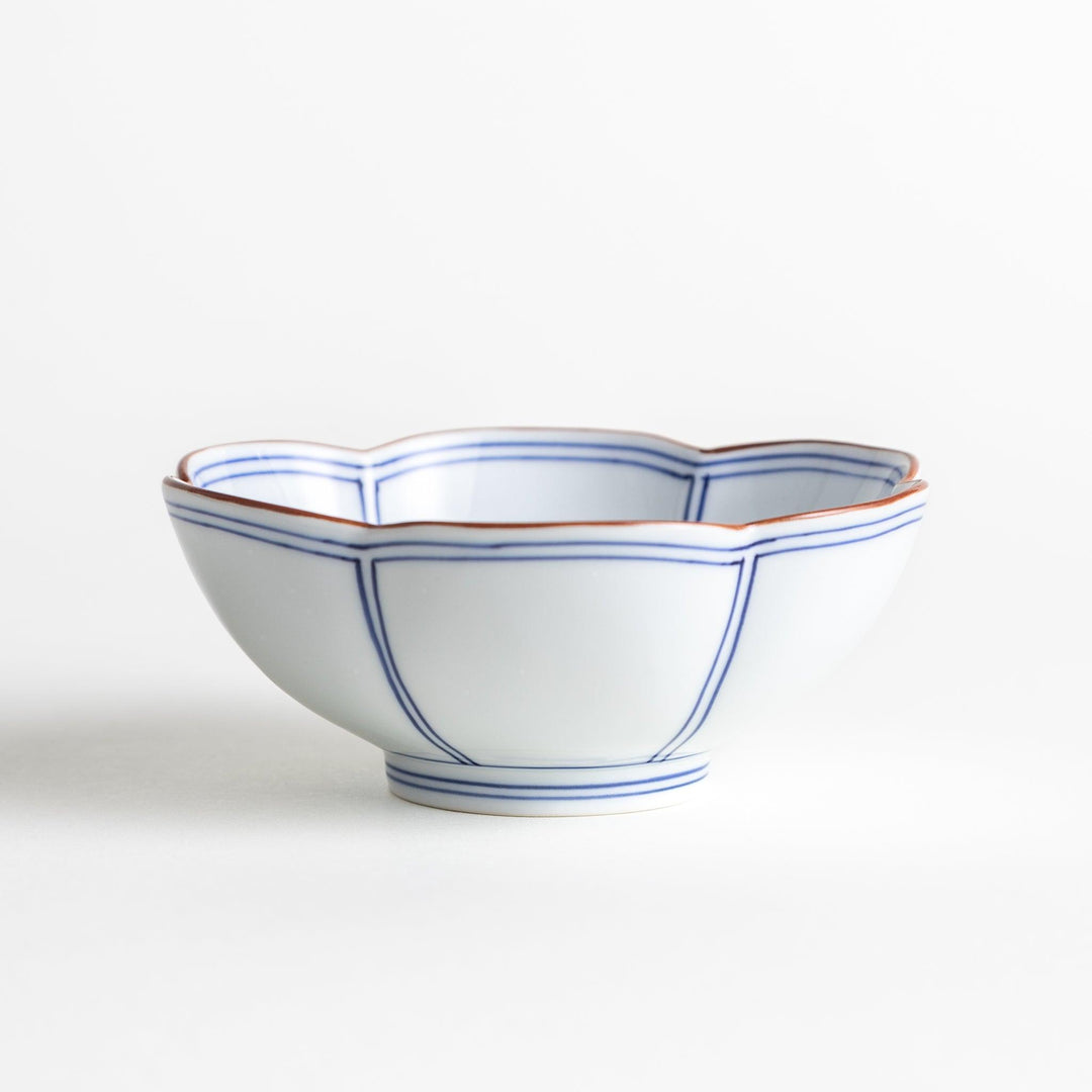 A white ceramic bowl with a floral shape, featuring delicate blue lines and an orange rim.