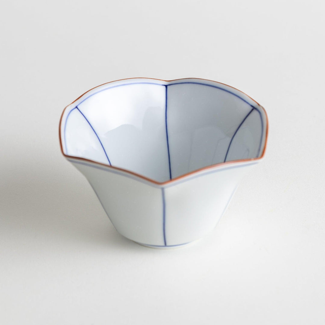 A white ceramic bowl with a flared, scalloped edge and simple blue line detailing.