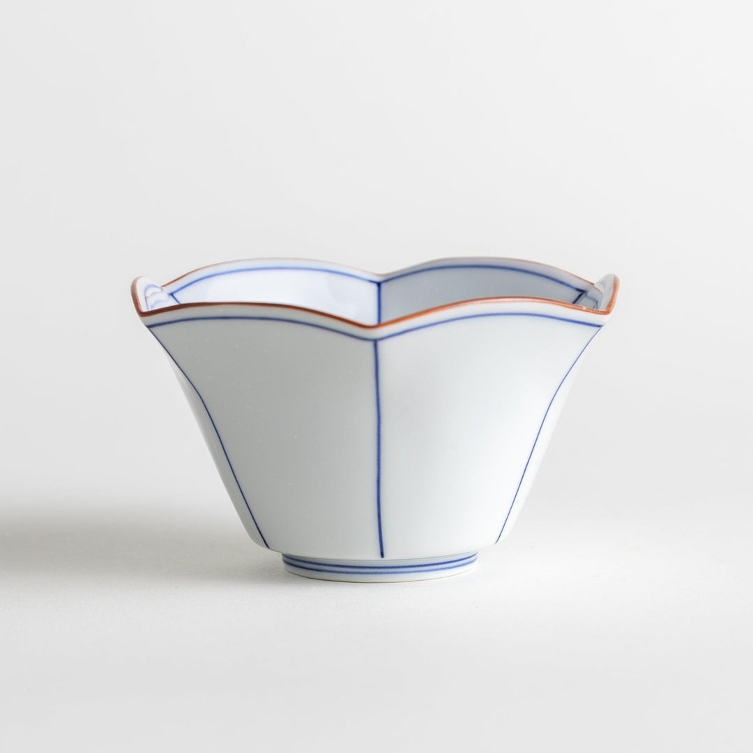 A white ceramic bowl with a flared, scalloped edge and simple blue line detailing.