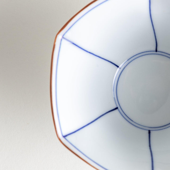 A white ceramic bowl with a flared, scalloped edge and simple blue line detailing.