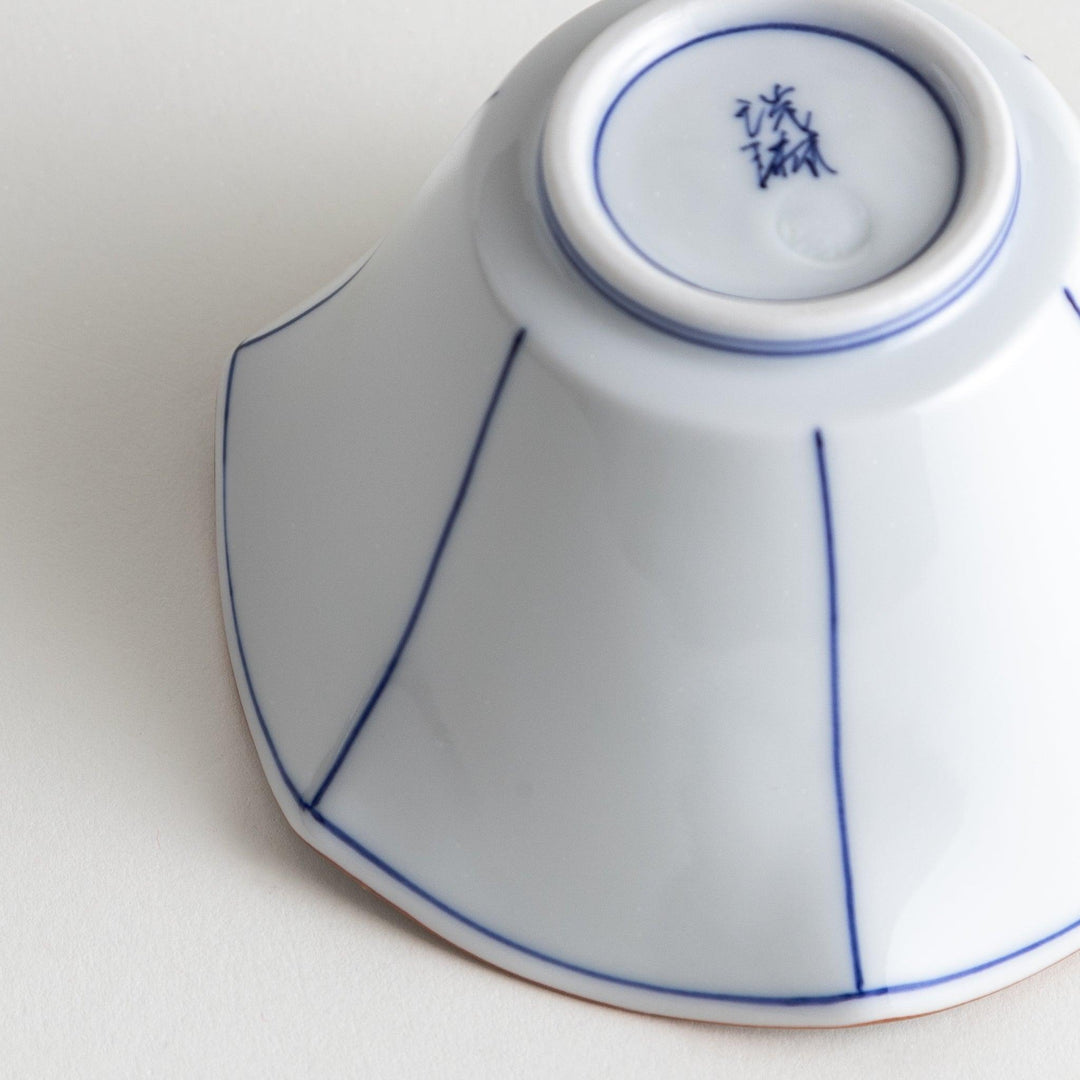 A white ceramic bowl with a flared, scalloped edge and simple blue line detailing.