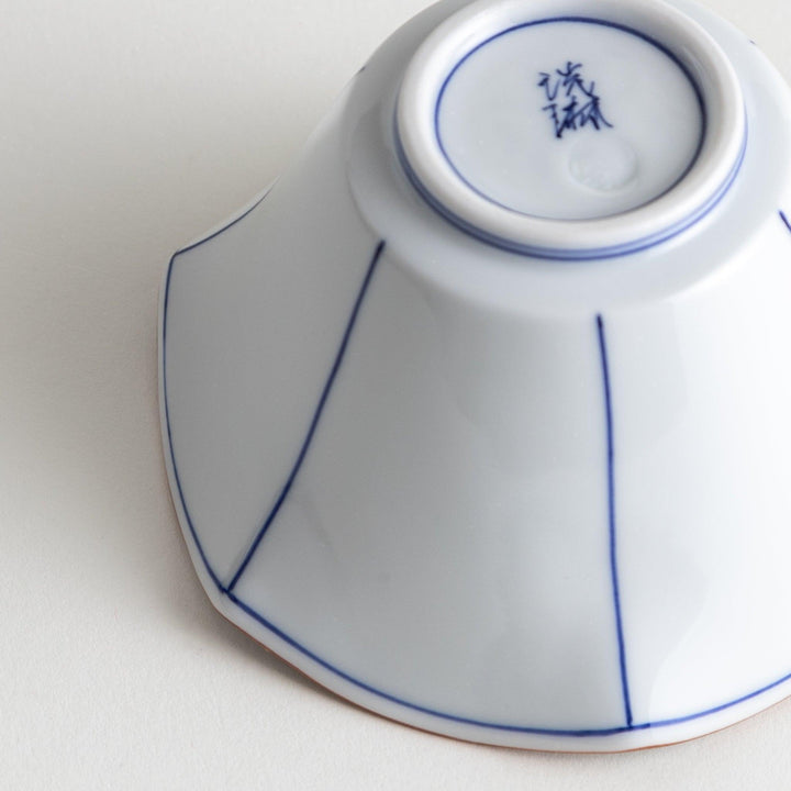 A white ceramic bowl with a flared, scalloped edge and simple blue line detailing.