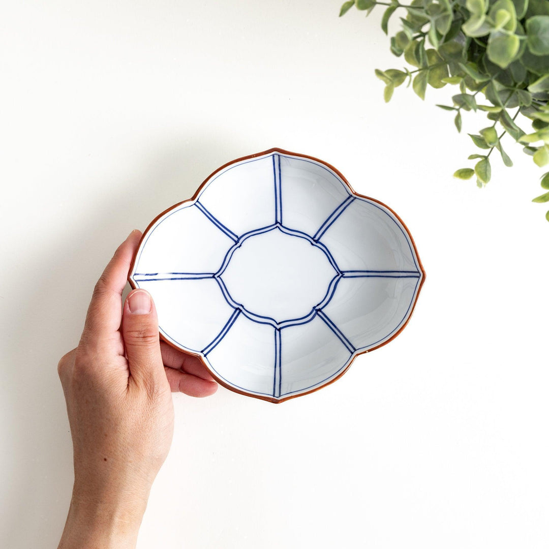 A ceramic bowl shaped like a quince with blue line detailing.