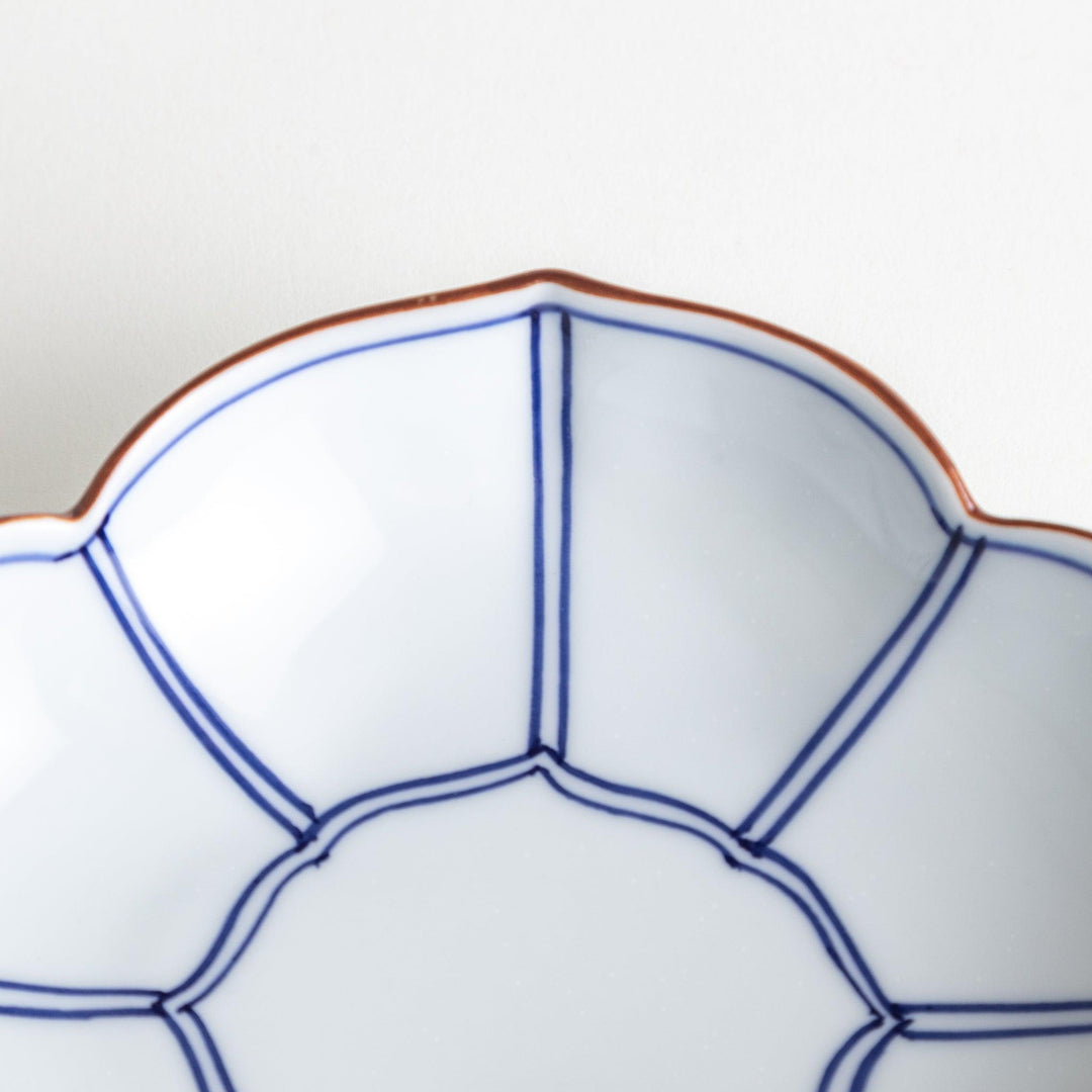 A ceramic bowl shaped like a quince with blue line detailing.