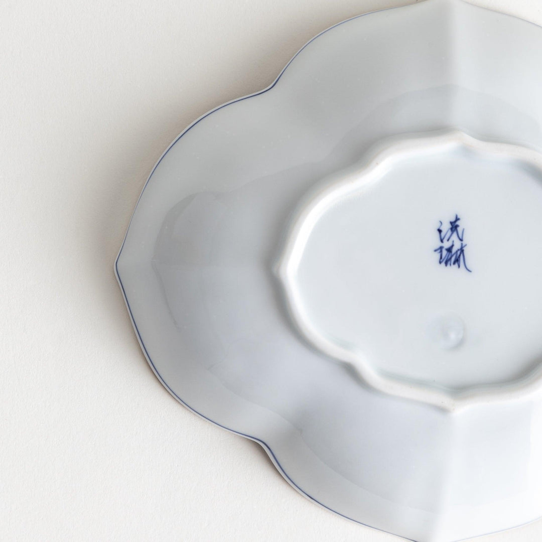 A ceramic bowl shaped like a quince with blue line detailing.