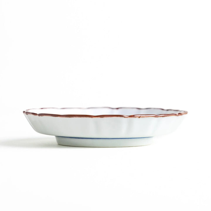 Side view of the porcelain sauce dish, highlighting its low pedestal base and delicate brown-edged raised rim.