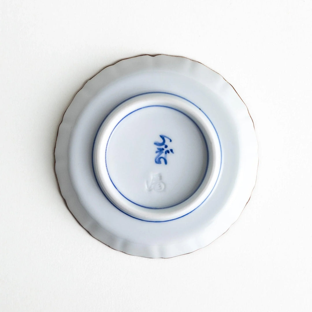 Bottom view of the sauce dish, showing the artist’s mark in blue and the raised base for stability.