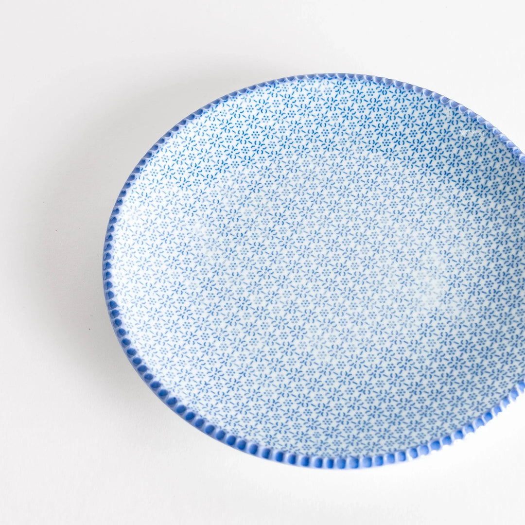 Close-up top view of the blue sesame salad plate, featuring a delicate pattern of blue flowers and a textured rim.