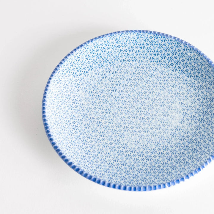 Close-up top view of the blue sesame salad plate, featuring a delicate pattern of blue flowers and a textured rim.