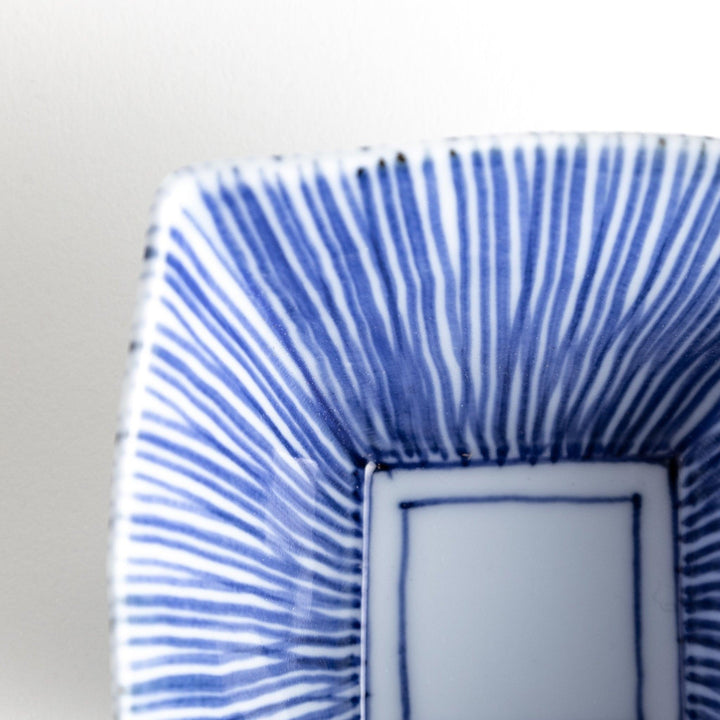 A small, square white plate with a geometric pattern of intersecting blue lines.