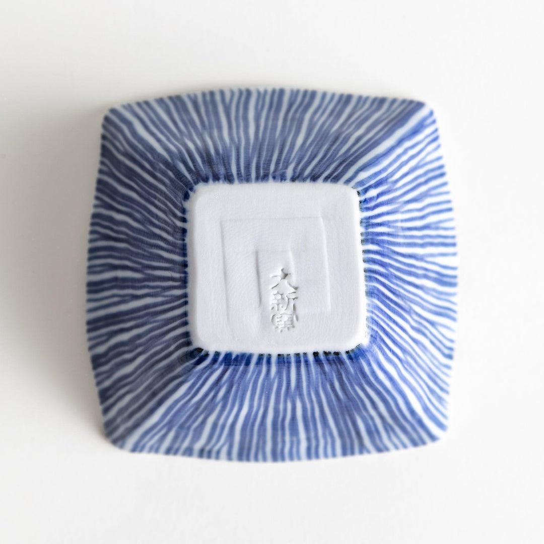 A small, square white plate with a geometric pattern of intersecting blue lines.