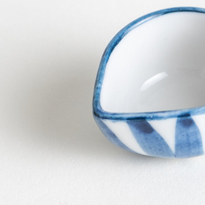 A small condiment bowl with a distinct blue and white vertical stripe pattern.