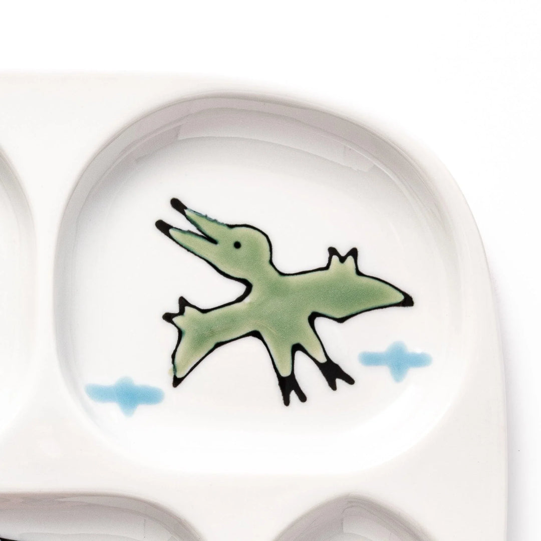 Japanese ceramic kids dinnerware set with pink dinosaur and green pterodactyl design including plate bowl and mug.