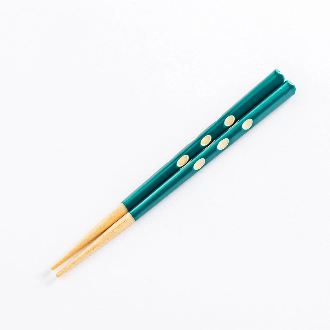 Single pair of green chopsticks with natural wood tips and dot pattern along the handle.