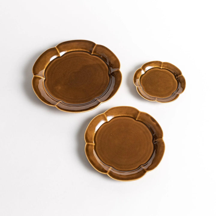 Three brown flower shaped ceramic plates in varying sizes with glossy finish and warm earthy tone.