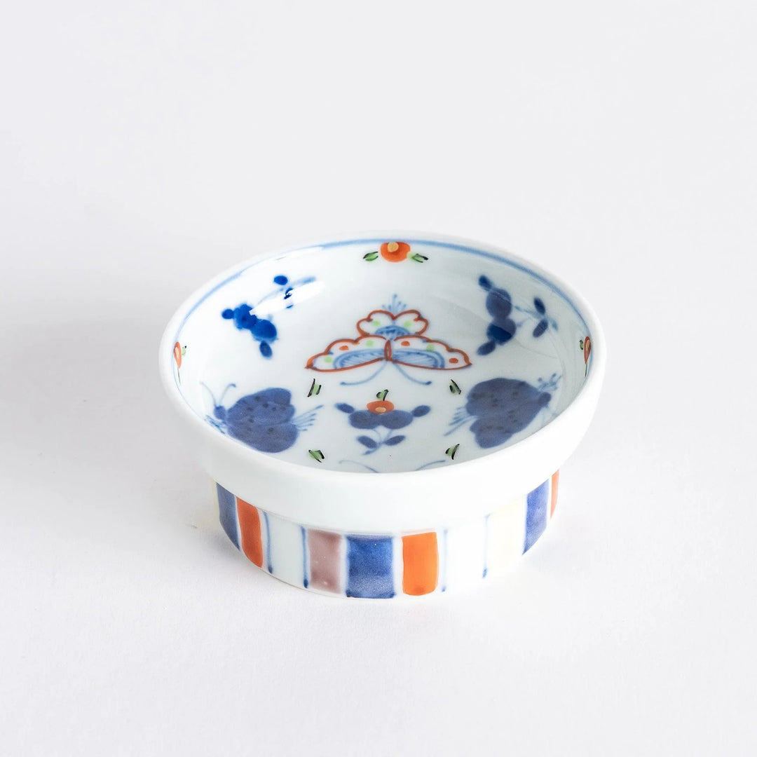 Petite raised Japanese sauce dish with colorful butterflies and floral designs and multicolored striped base.