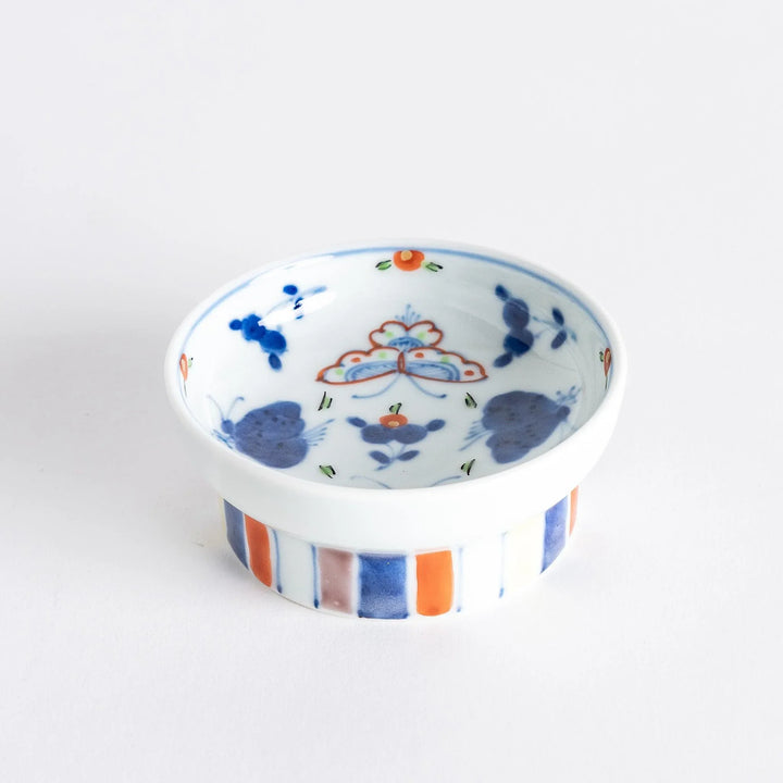 Petite raised Japanese sauce dish with colorful butterflies and floral designs and multicolored striped base.
