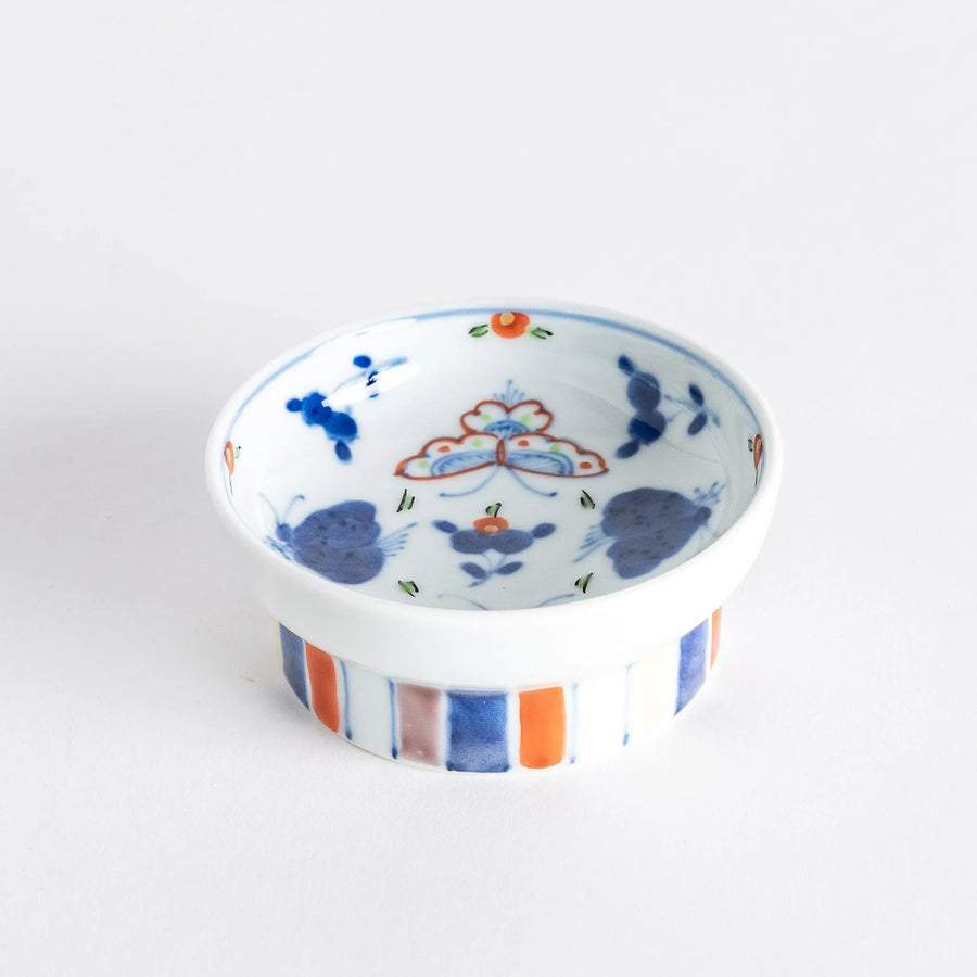 Petite raised Japanese sauce dish with colorful butterflies and floral designs and multicolored striped base.
