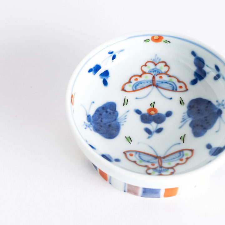 Petite raised Japanese sauce dish with colorful butterflies and floral designs and multicolored striped base.