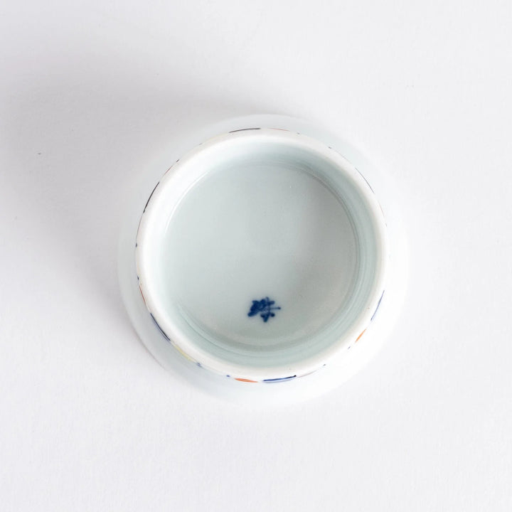 Petite raised Japanese sauce dish with colorful butterflies and floral designs and multicolored striped base.