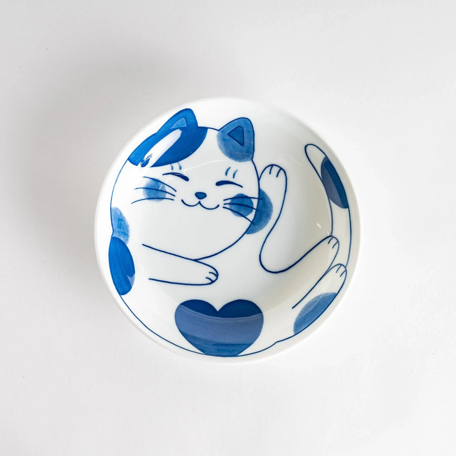A cereal bowl with a cheerful blue and white cat, playfully kicking its leg up.