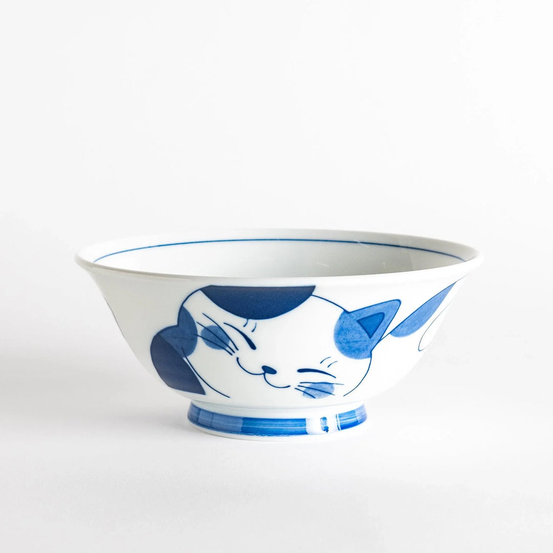 A white ramen bowl with a blue design of a cat with its ears back, looking relaxed.