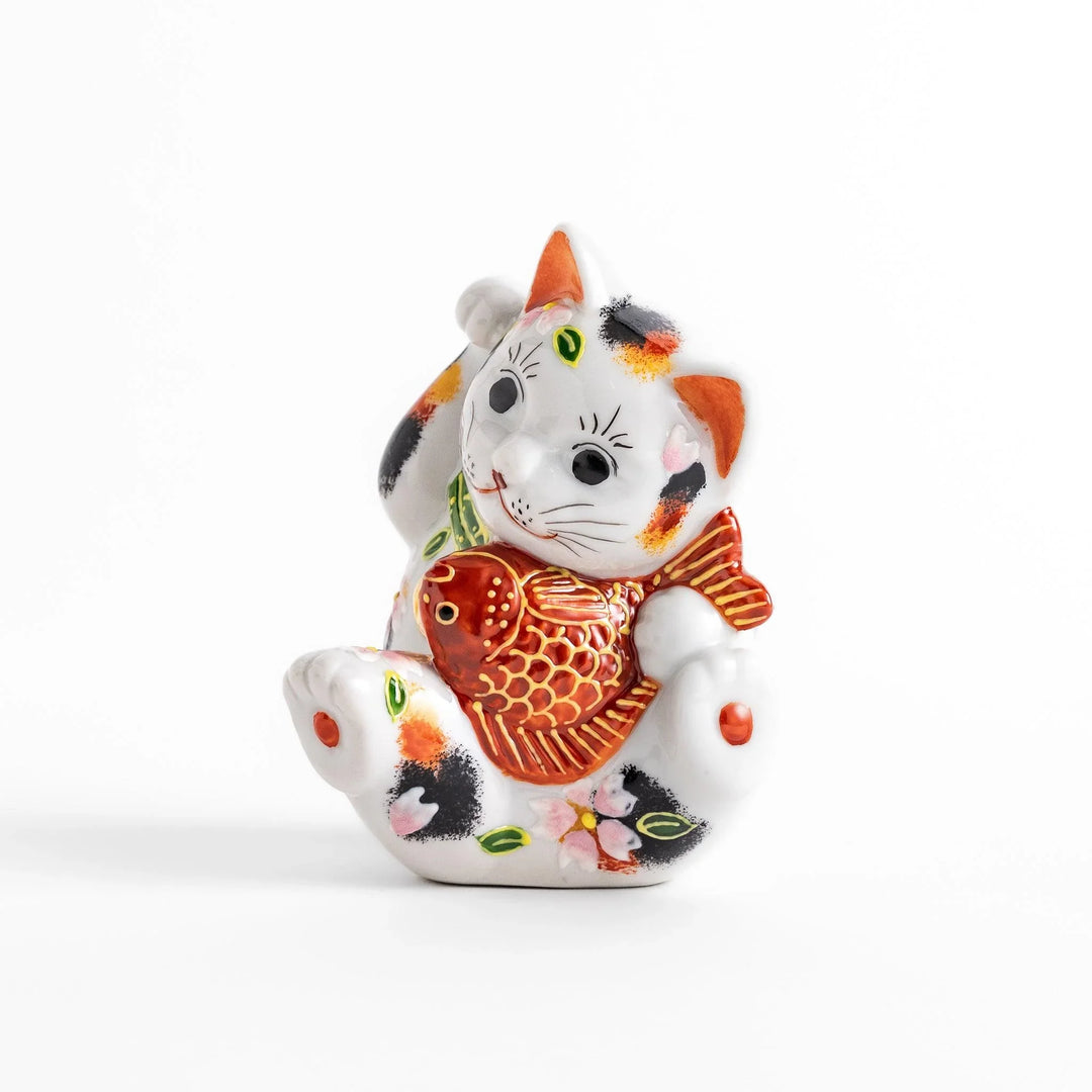 Calico Maneki Neko holding lucky sea bream with floral and leaf patterns symbolizing fortune and prosperity.