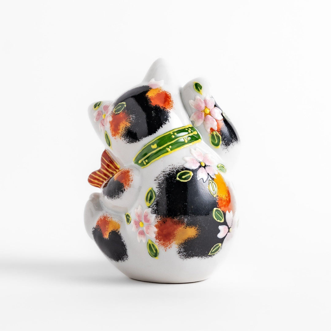 Calico Maneki Neko holding lucky sea bream with floral and leaf patterns symbolizing fortune and prosperity.
