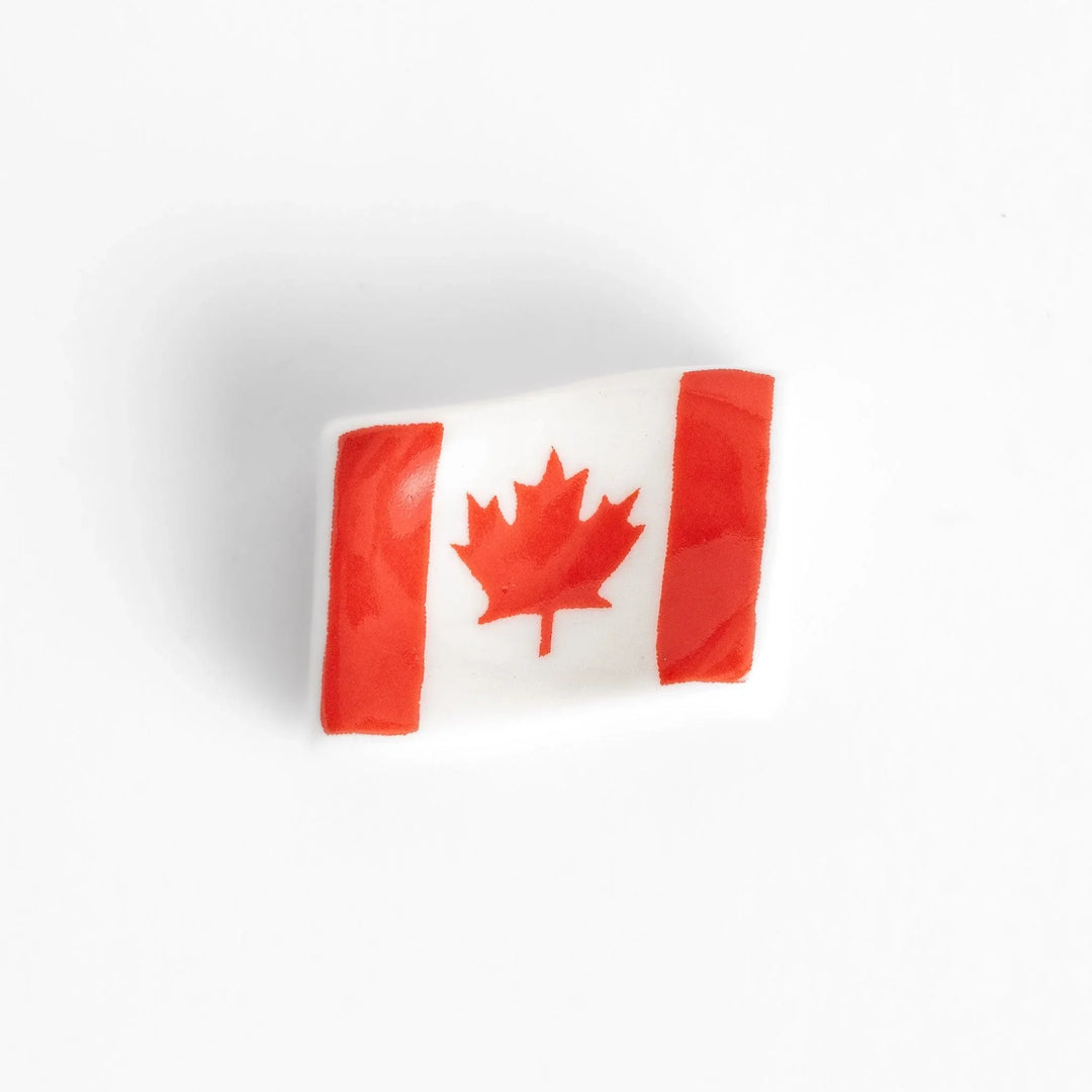 Chopstick rest shaped like the Canadian flag, featuring a red maple leaf in the center, with red borders on each side.