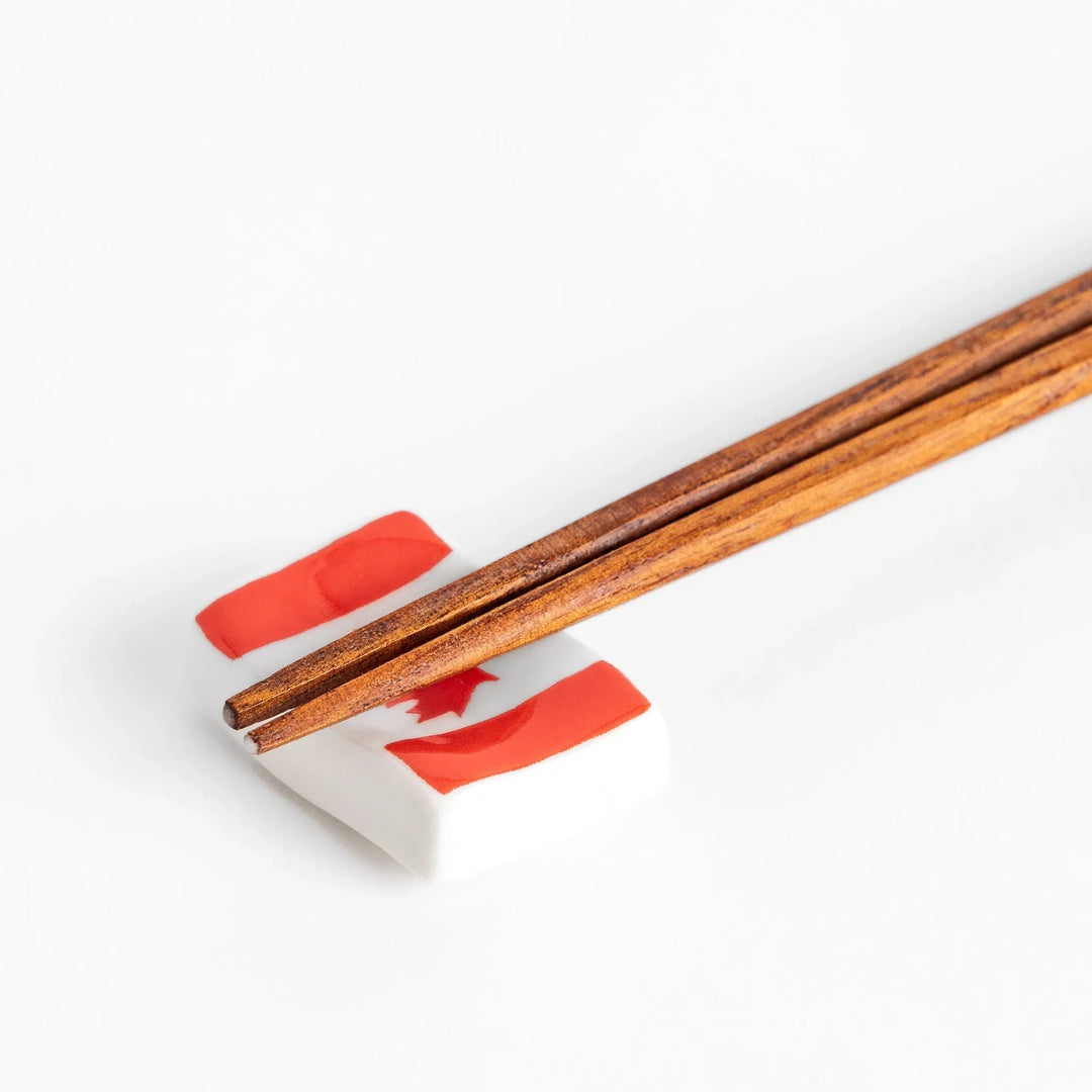 Chopstick rest shaped like the Canadian flag, featuring a red maple leaf in the center, with red borders on each side.