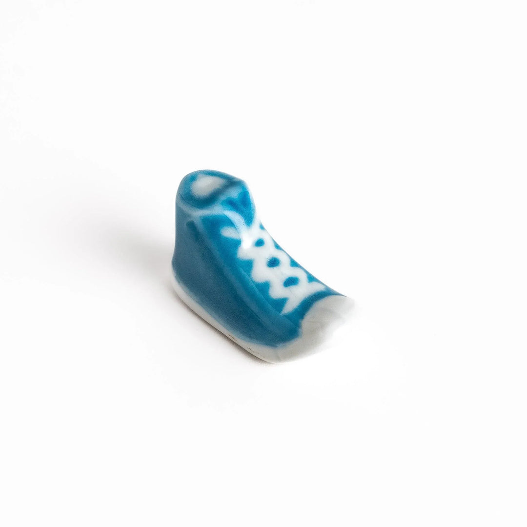 Canvas sneaker shaped ceramic chopstick rest featuring detailed laces and sole design adding playful touch to dining.