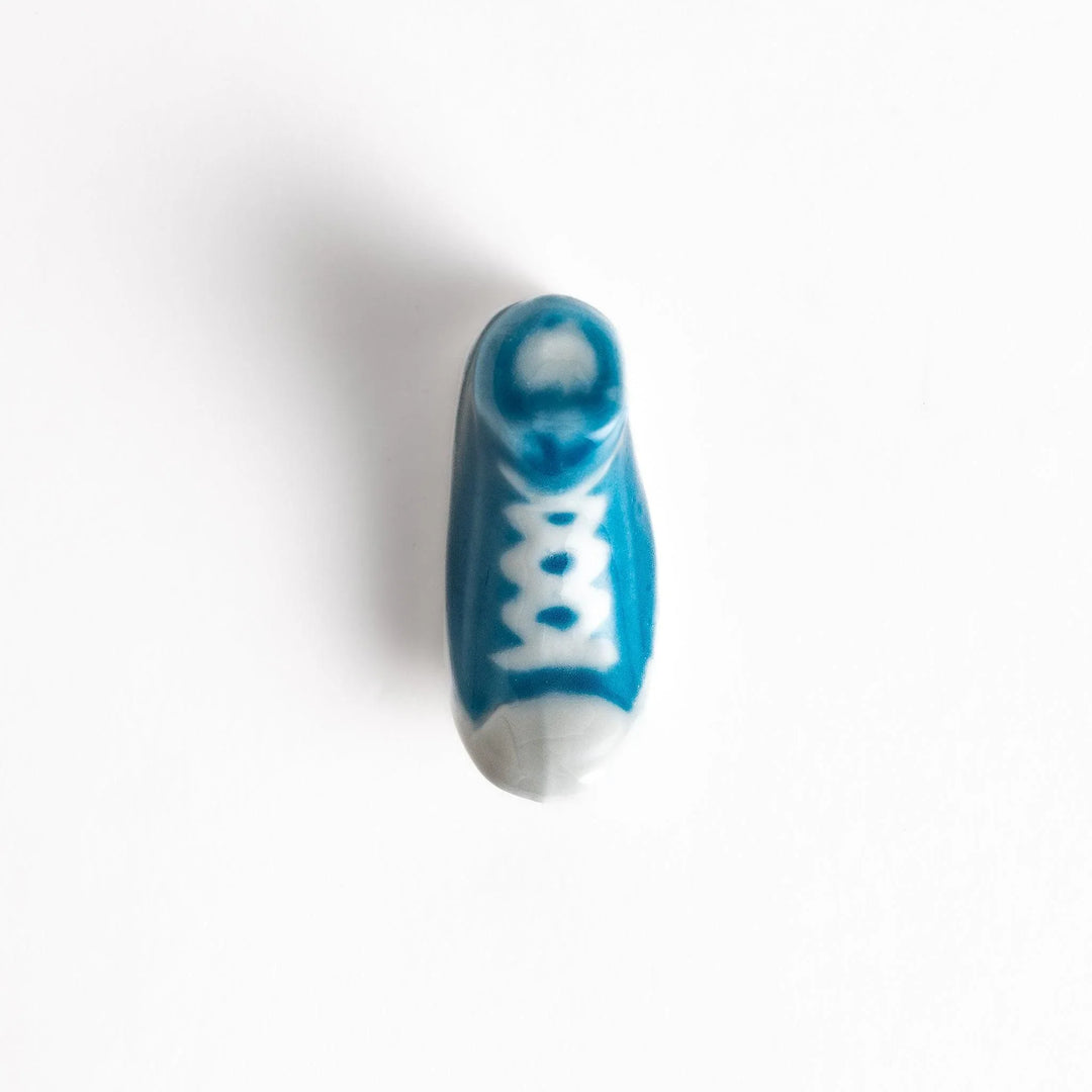 Canvas sneaker shaped ceramic chopstick rest featuring detailed laces and sole design adding playful touch to dining.