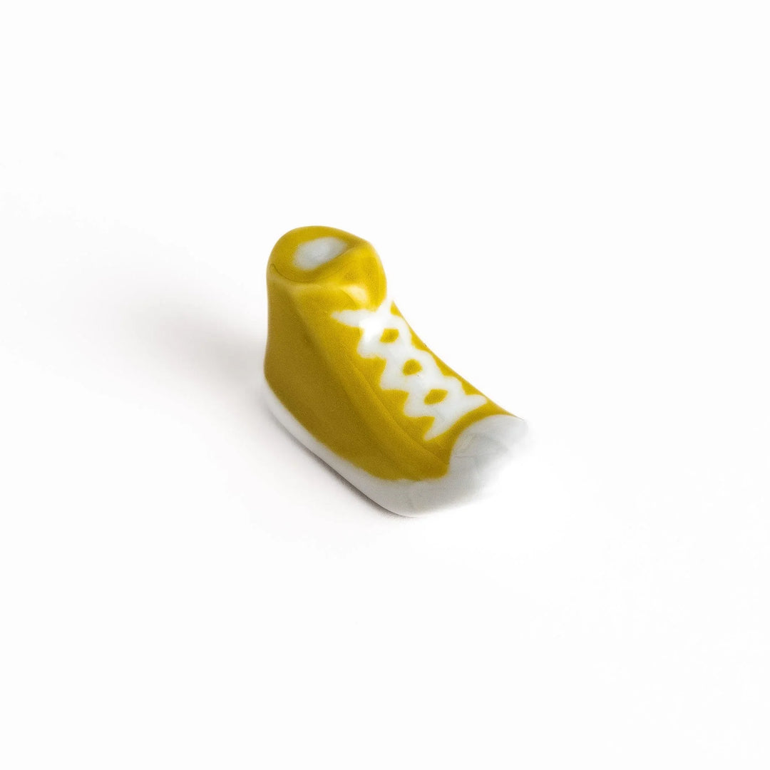 Canvas sneaker shaped ceramic chopstick rest featuring detailed laces and sole design adding playful touch to dining.