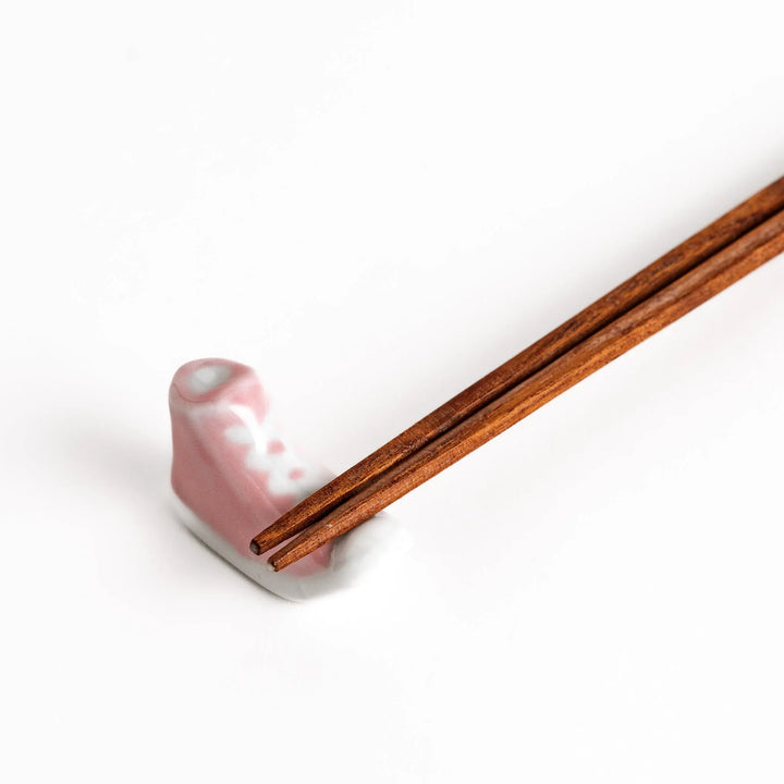 Pink Canvas Sneaker Chopstick Rest holding wooden chopsticks, showcasing its vibrant design and practical functionality.