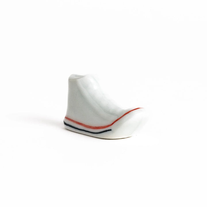 Canvas sneaker shaped ceramic chopstick rest featuring detailed laces and sole design adding playful touch to dining.