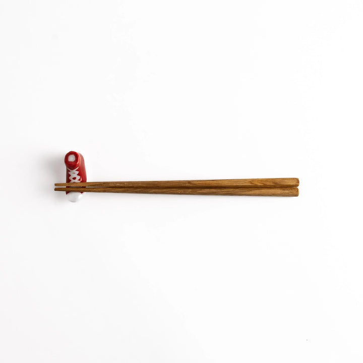 Red Canvas Sneaker Chopstick Rest holding wooden chopsticks, showcasing its vibrant design and practical functionality.
