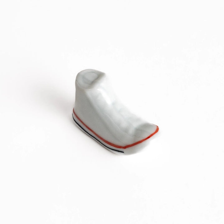 Canvas sneaker shaped ceramic chopstick rest featuring detailed laces and sole design adding playful touch to dining.