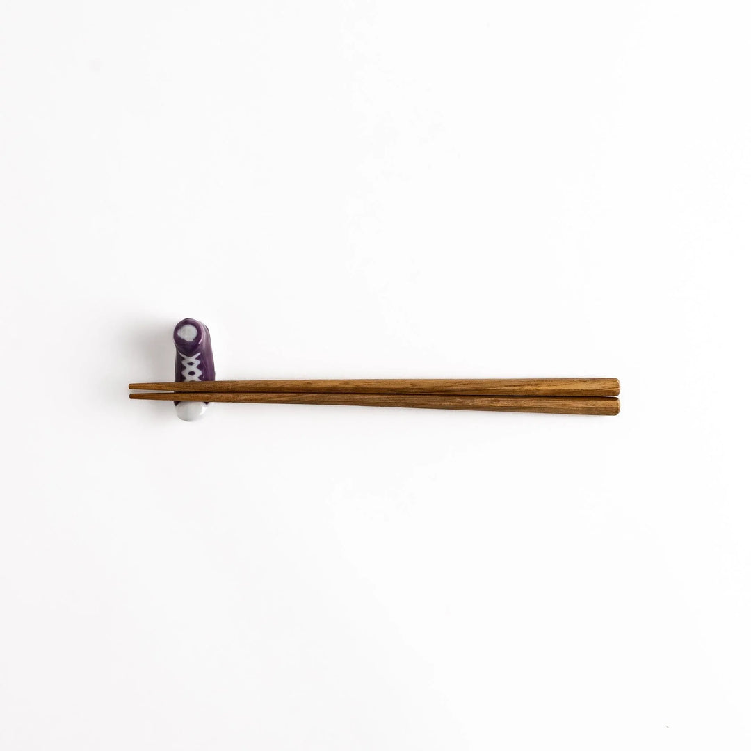 Purple Canvas Sneaker Chopstick Rest holding wooden chopsticks, showcasing its vibrant design and practical functionality.