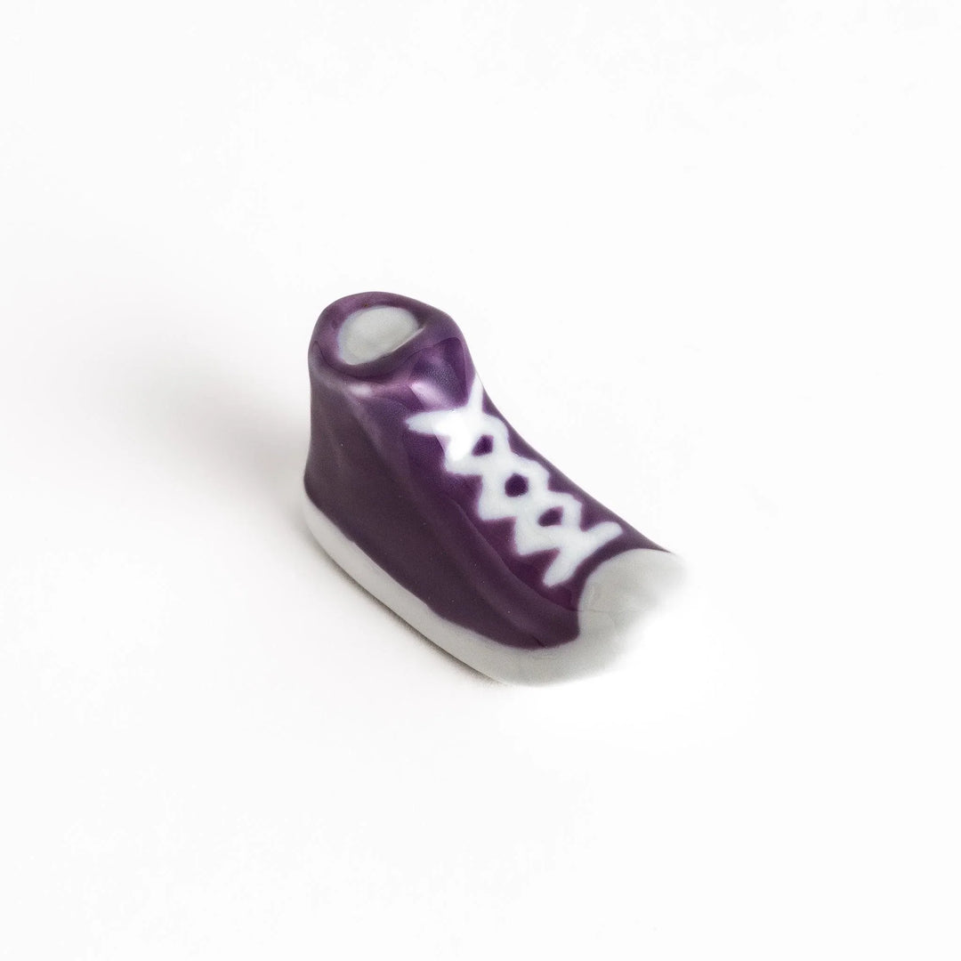 Canvas sneaker shaped ceramic chopstick rest featuring detailed laces and sole design adding playful touch to dining.