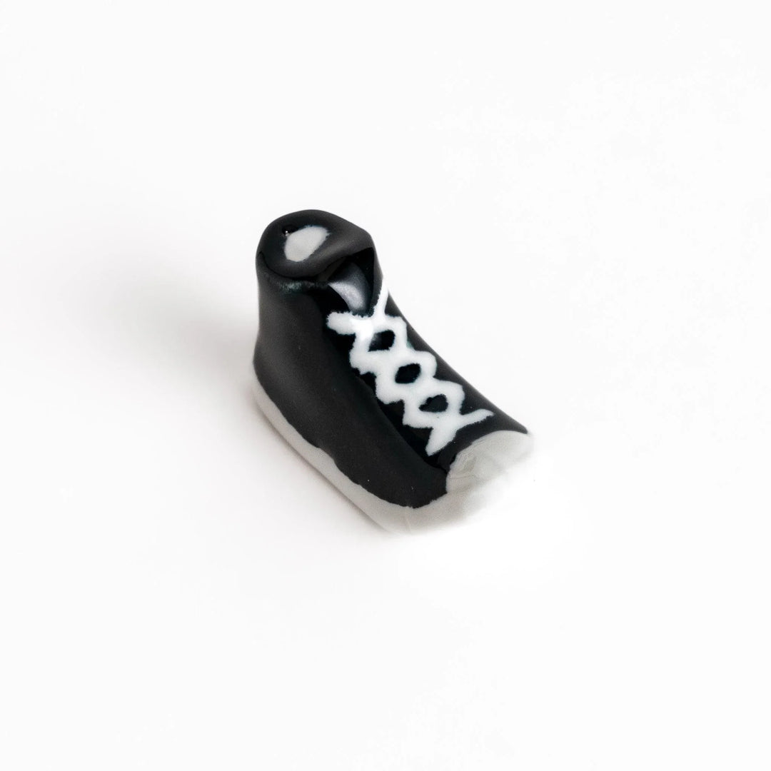 Canvas sneaker shaped ceramic chopstick rest featuring detailed laces and sole design adding playful touch to dining.