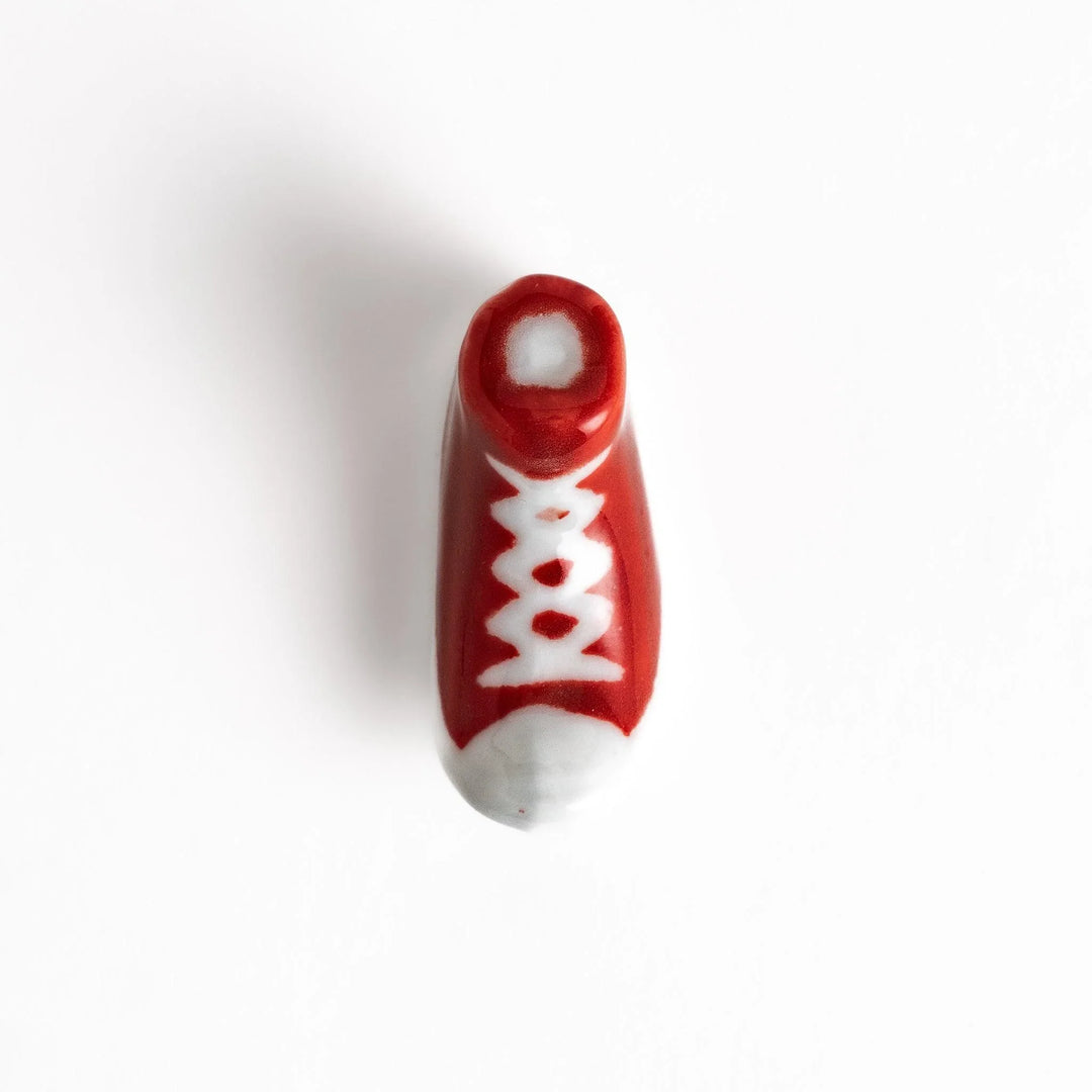 Canvas sneaker shaped ceramic chopstick rest featuring detailed laces and sole design adding playful touch to dining.