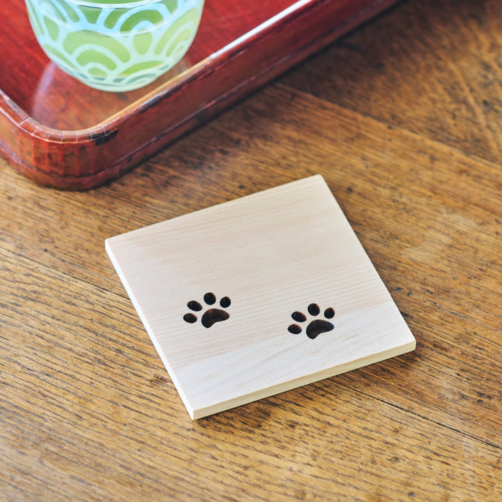 Close up of a handcrafted Japanese cedar wood mini coaster with adorable cat paw print cutouts showing wood grain
