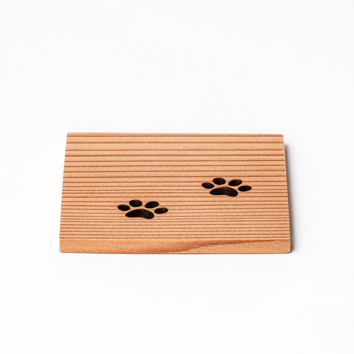 Square cedar mini coaster with two laser-cut cat paw prints, natural warm wood grain, perfect for small cups or glasses.