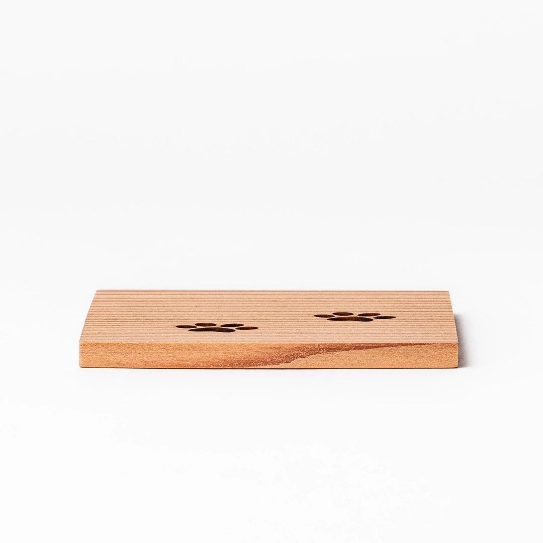 Square cedar mini coaster with two laser-cut cat paw prints, natural warm wood grain, perfect for small cups or glasses.
