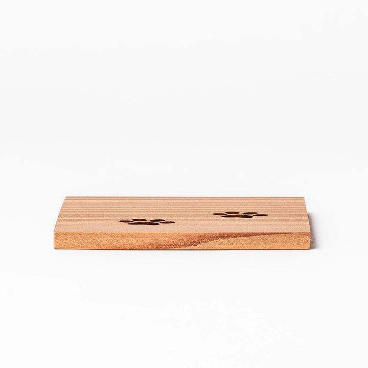 Square cedar mini coaster with two laser-cut cat paw prints, natural warm wood grain, perfect for small cups or glasses.