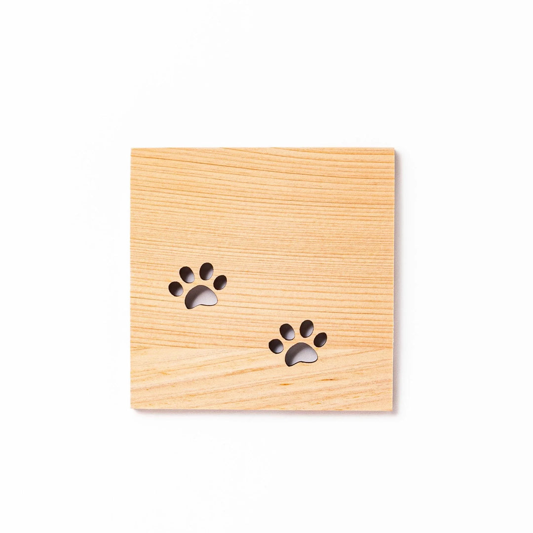 Square hinoki wood mini coaster with two cat paw cutouts, showcasing light grain and protecting surfaces.