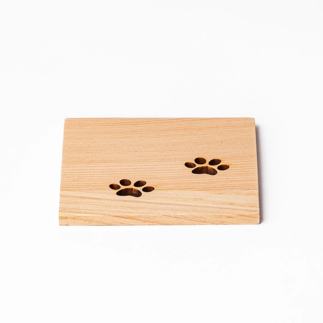 Square hinoki wood mini coaster with two cat paw cutouts, showcasing light grain and protecting surfaces.