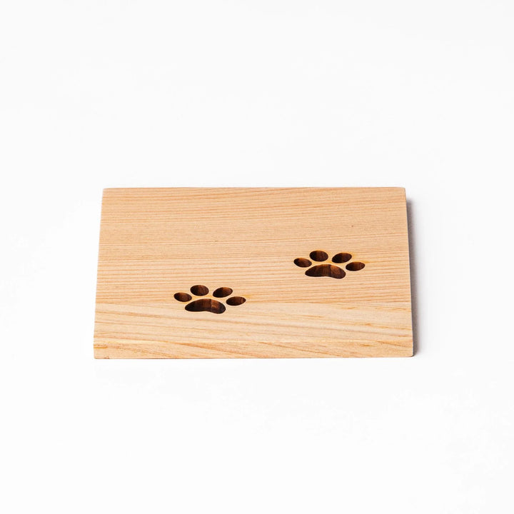 Square hinoki wood mini coaster with two cat paw cutouts, showcasing light grain and protecting surfaces.