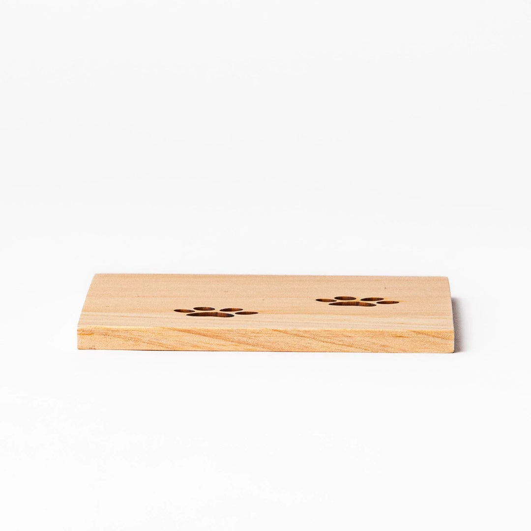 Square hinoki wood mini coaster with two cat paw cutouts, showcasing light grain and protecting surfaces.